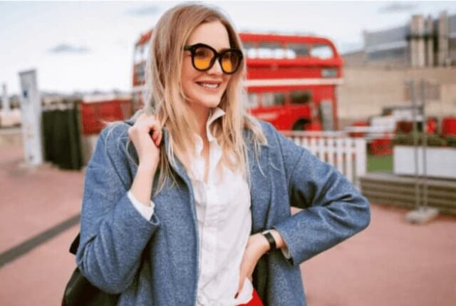 Arka planda kırmızı İngiliz otobüsleri olan bir kadın.