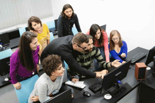 Bir grup öğrenci, bilgisayar etrafında toplanarak projeleri üzerinde çalışıyor.