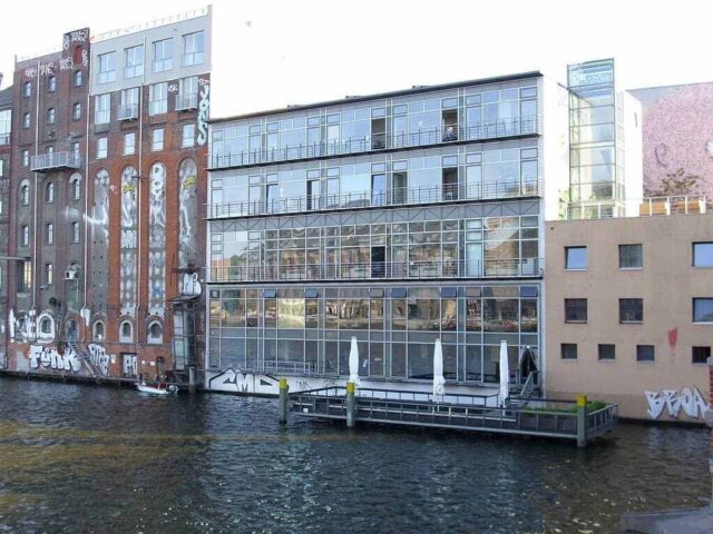 Dere kenarında sıralanmış binaların manzarası.